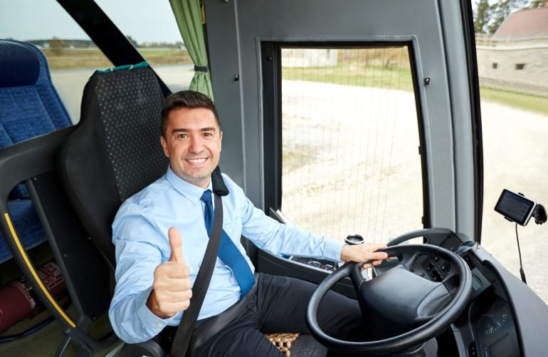 transport, tourism, road trip and people concept - happy driver driving intercity bus and snowing thumbs up